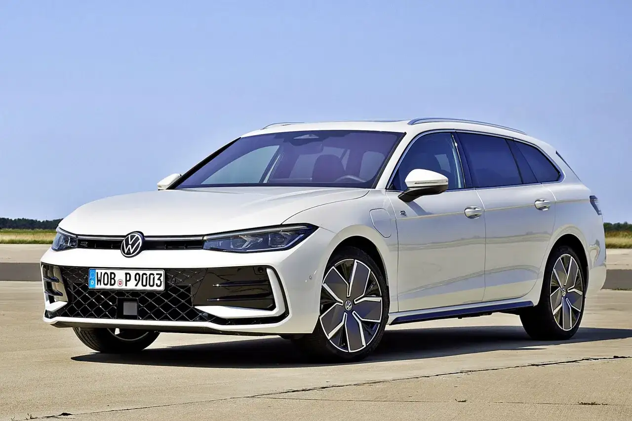 Biały Volkswagen Passat sedan z nowoczesnymi felgami stoi na betonowej nawierzchni, z błękitnym niebem w tle.