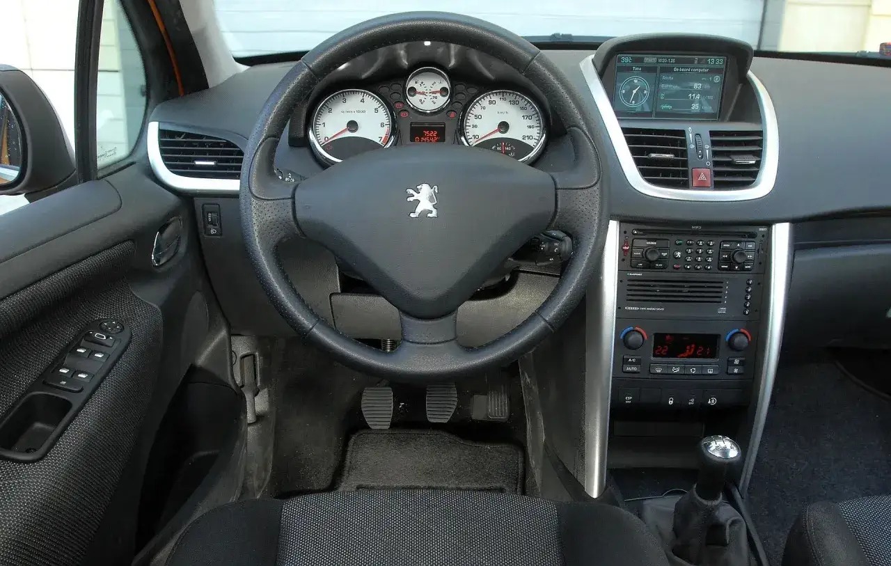 Wnętrze Peugeota 207, kierownica, deska rozdzielcza z komputerem pokładowym i radiem. Wiele osób szuka peugeot 207 opinie, ten widok pokazuje jego wnętrze.