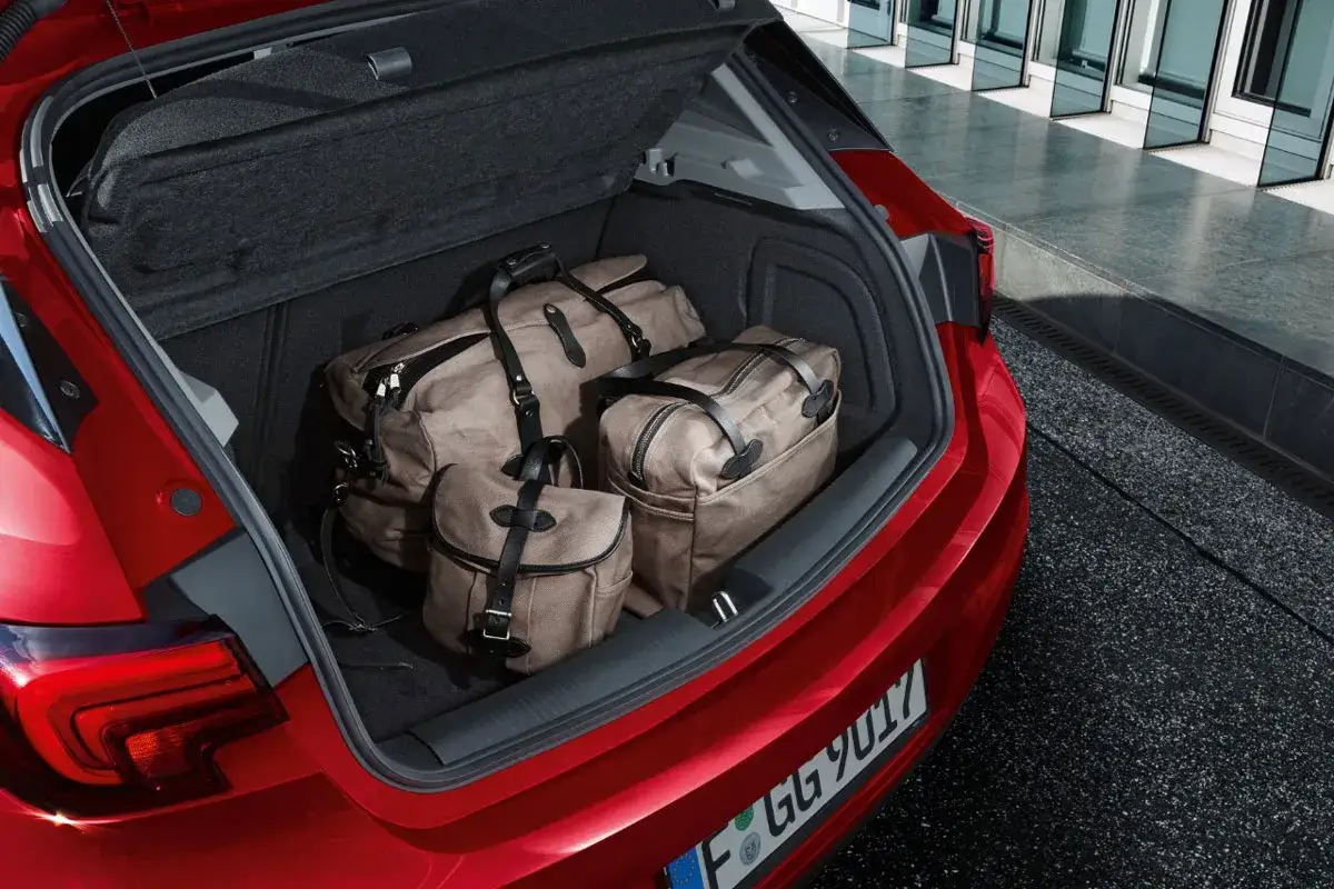 Bagażnik czerwonego Opla Astry J hatchback pomieścił trzy stylowe torby podróżne.
