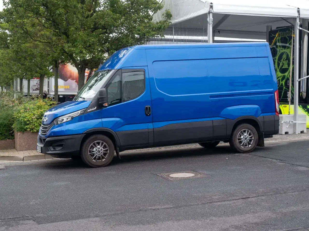 Błękitny Iveco Daily 3 z przyciemnianymi szybami stoi na ulicy.