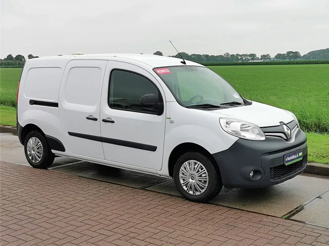 Biały Renault Kangoo 1.5 dCi gotowy do pracy na tle zielonych pól.