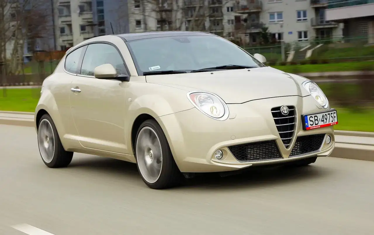 Złoty Alfa Romeo MiTo w ruchu ulicznym. Wiele osób szuka alfa romeo mito opinie, by poznać ten model.