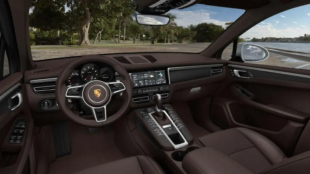 Wnętrze Porsche Macan w brązowej skórze. Kierownica, deska rozdzielcza z ekranem i konsola środkowa. Zastanawiasz się nad porsche macan cena?