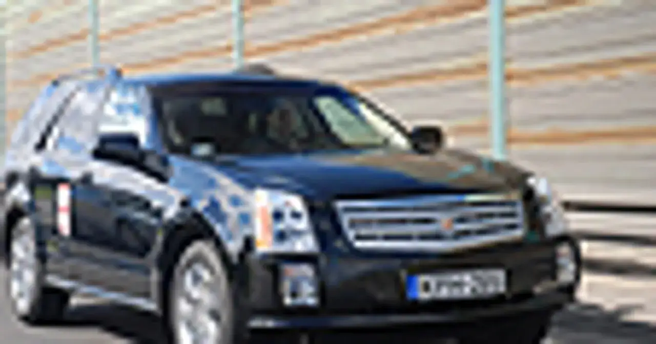 Czarny Cadillac SRX jedzie po drodze.