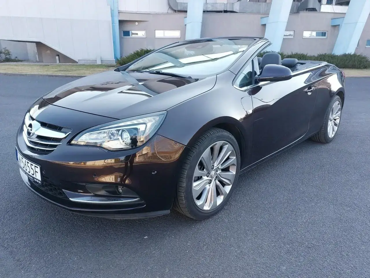 Ciemnobrązowy Opel Astra Cabrio z opuszczonym dachem, gotowy na letnią przejażdżkę.