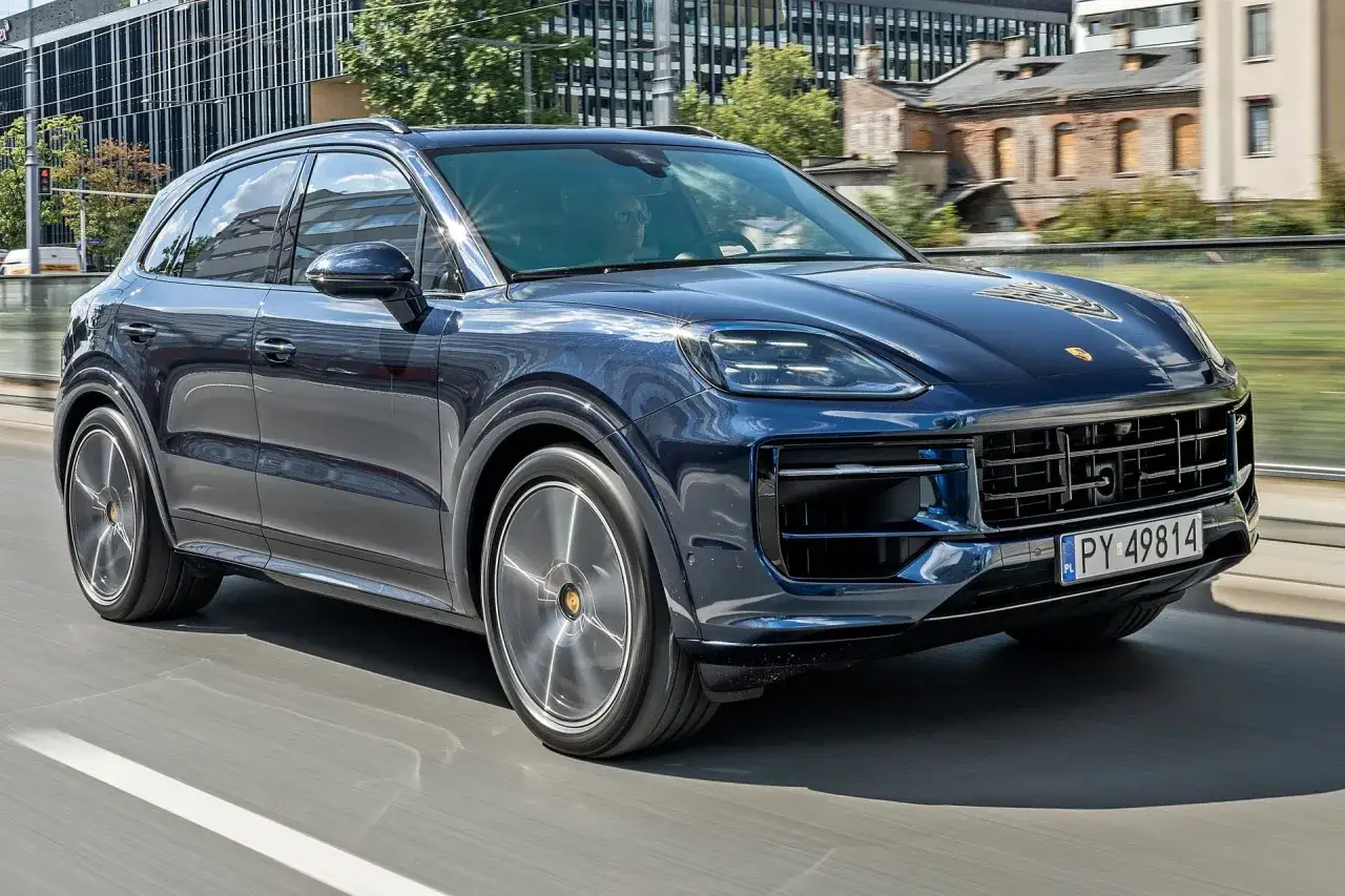 Elegancki, ciemnoniebieski Porsche Cayenne w ruchu miejskim. Sprawdź aktualną porsche cayenne cena.