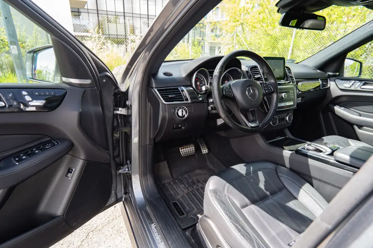 Wnętrze luksusowego Mercedesa GLE 400d z czarną skórzaną tapicerką, nowoczesną deską rozdzielczą i kierownicą.