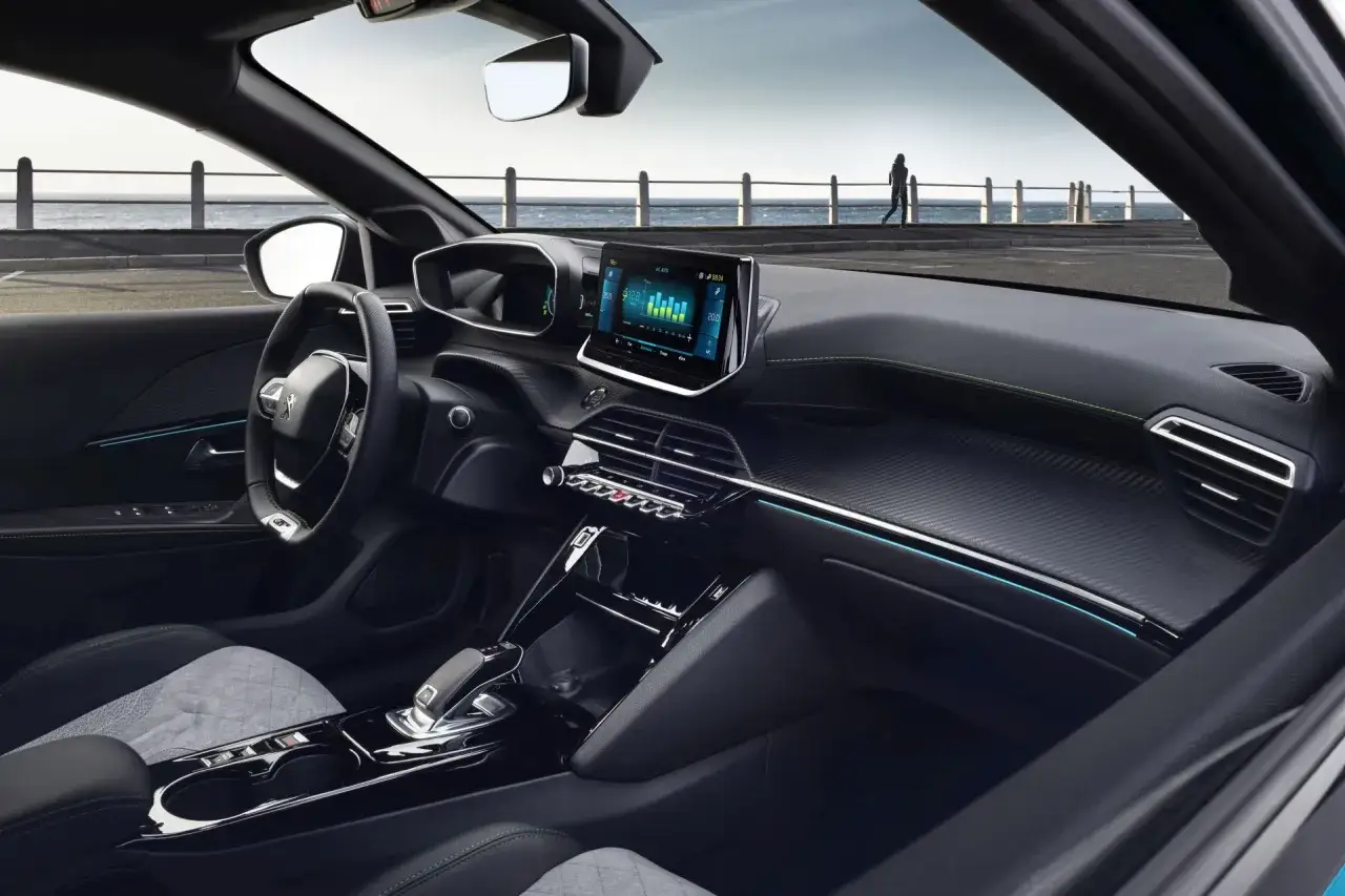 Wnętrze Peugeot e-208 z ekranem multimedialnym i widokiem na morze.