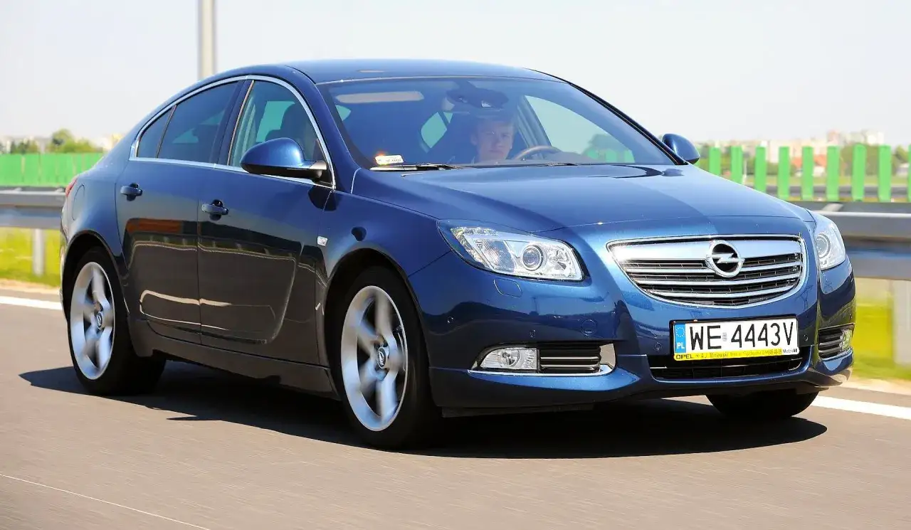 Niebieski Opel Insignia w ruchu drogowym. Kierowca za kierownicą. Wiele pozytywnych opinii o tym modelu.