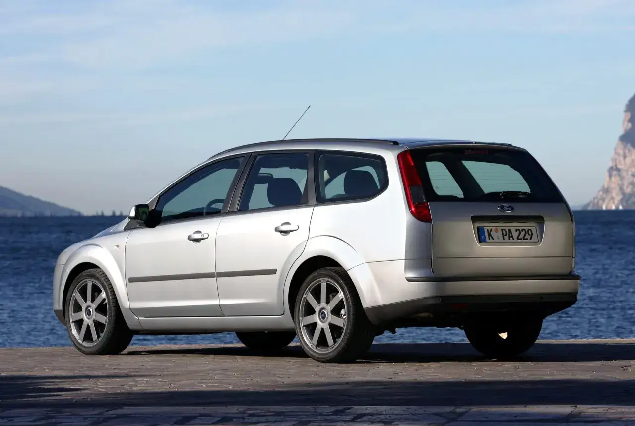 Srebrny Ford Focus MK2 1.6 benzyna kombi zaparkowany nad wodą.