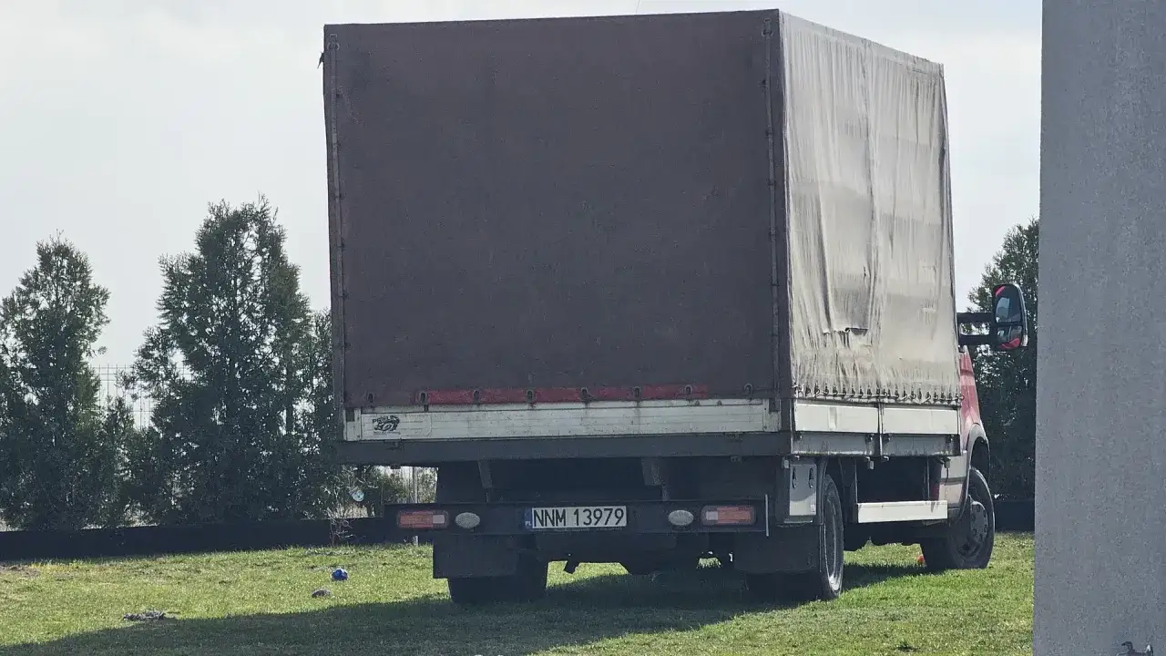 Ciężarówka z plandeką, tył. Widoczna tablica rejestracyjna NNM 13979.