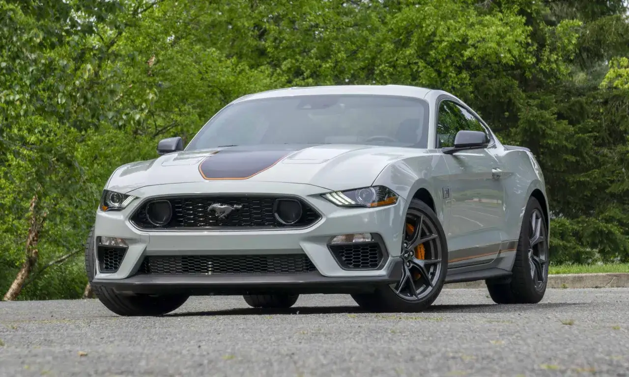 Szary Ford Mustang Mach 1 z pomarańczowymi akcentami, gotowy do osiągnięcia prędkości mach 1.