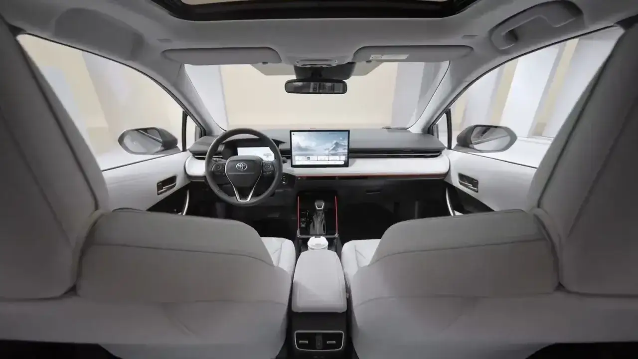 Wnętrze nowoczesnej toyoty corolla sedan z dużym ekranem multimedialnym i jasnymi siedzeniami.