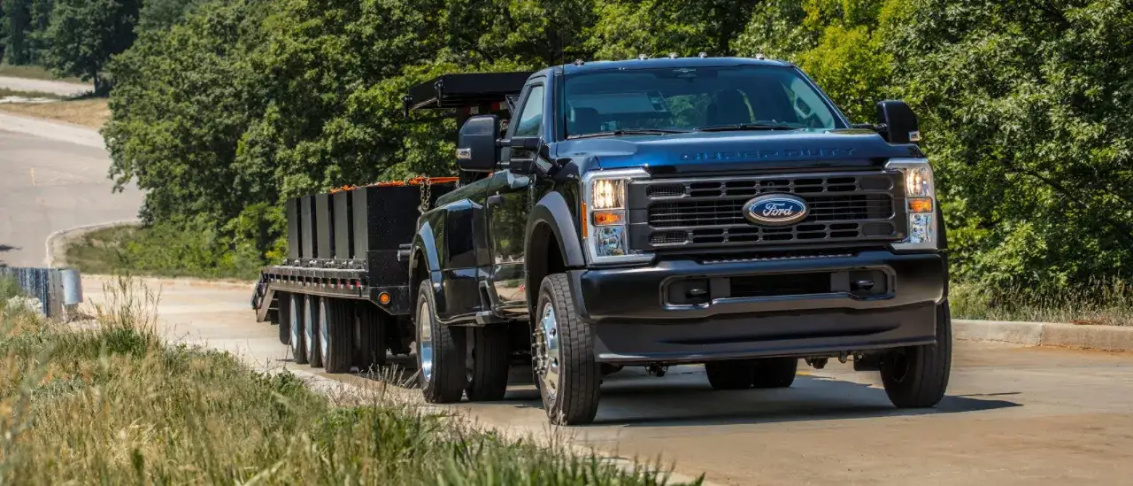 Czarny Ford Super Duty z przyczepą pełną ciężkich ładunków, gotowy do pracy w trudnym terenie.