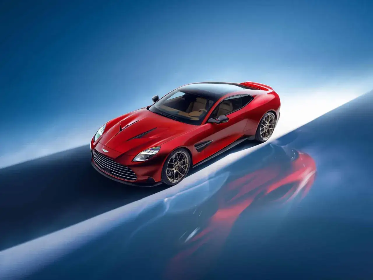 Czerwony Aston Martin Vanquish z beżowym wnętrzem, lśniącym na tle niebieskiego gradientu.