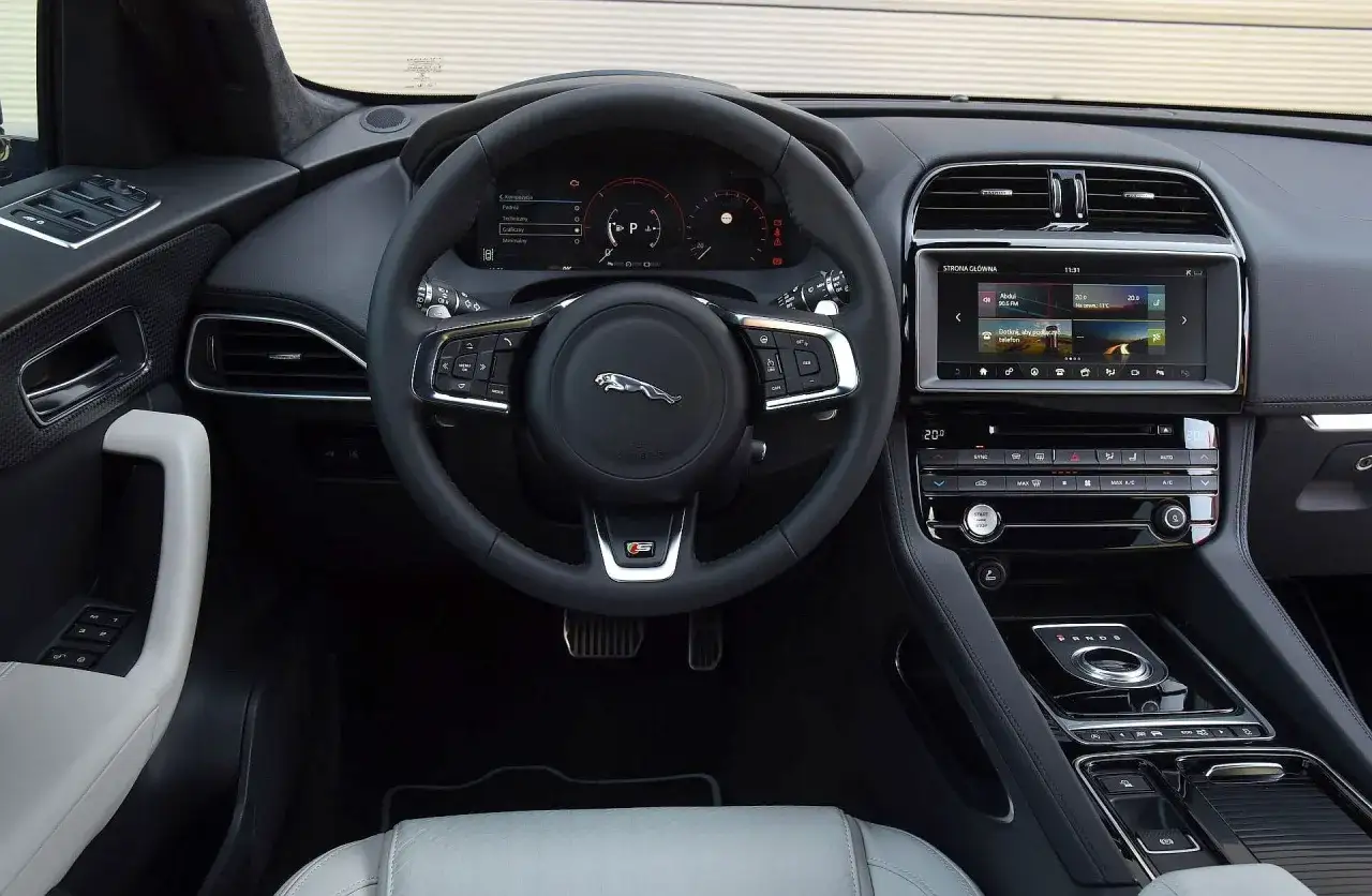 Wnętrze Jaguar F-Pace: nowoczesna deska rozdzielcza, ekran multimediów i kierownica. Opinie o komforcie i technologii są pozytywne.