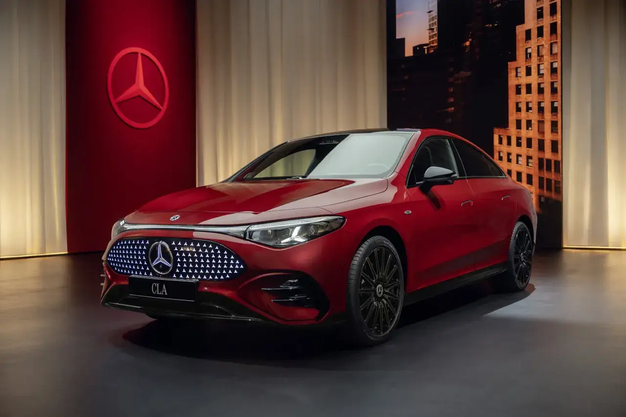 Nowy Mercedes CLA w lśniącym, czerwonym kolorze prezentuje się na tle miejskiego krajobrazu.
