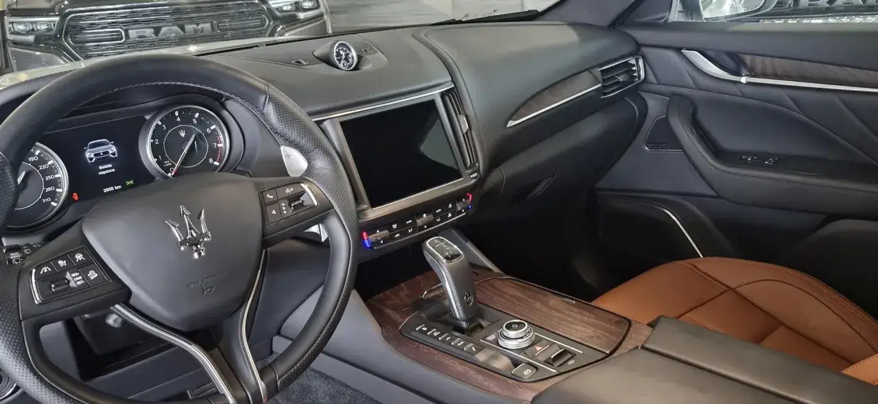 Wnętrze Maserati Levante, skórzana kierownica, ekran multimediów i drewniane akcenty. Idealny wybór, jeśli szukasz informacji o Maserati Levante cena.