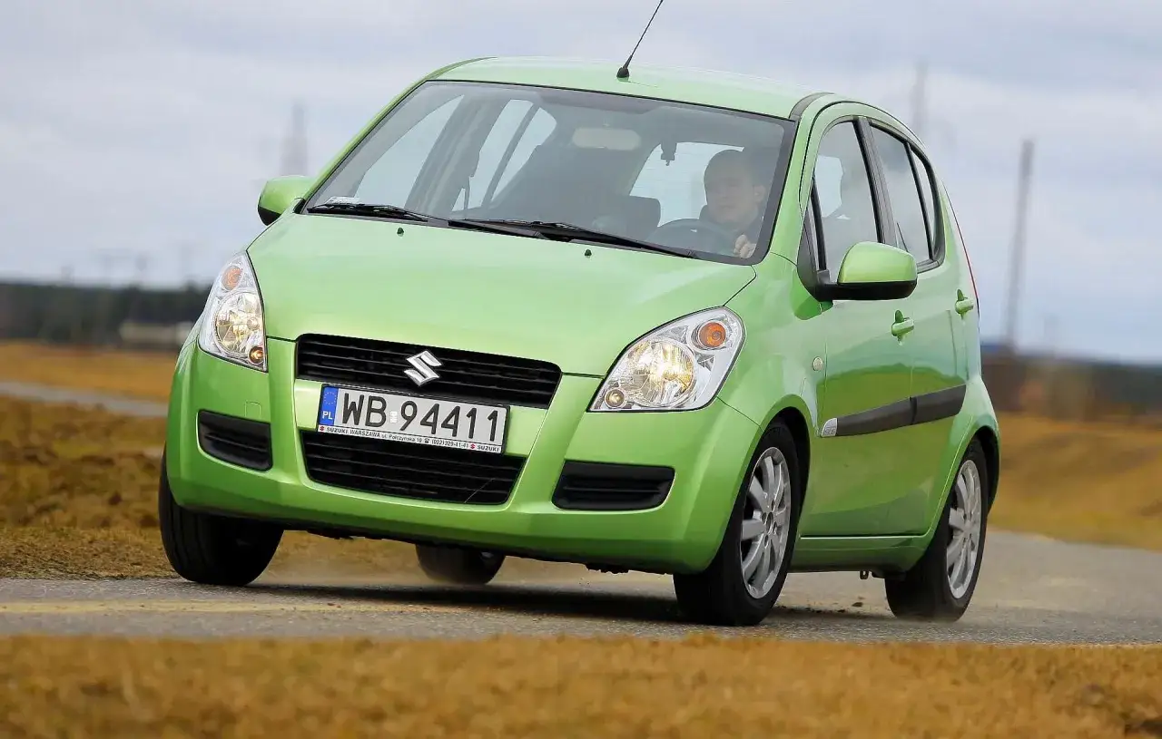 Zielony Opel Agila 1.2 z polskimi tablicami rejestracyjnymi WB 94411 jedzie po drodze.