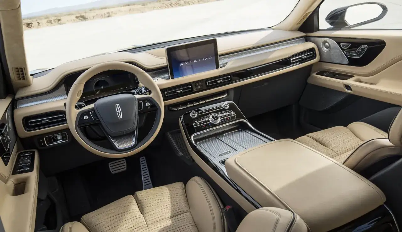Wnętrze Lincoln Aviator: skórzana kierownica, ekran dotykowy z logo Aviator, jasne fotele i deska rozdzielcza.