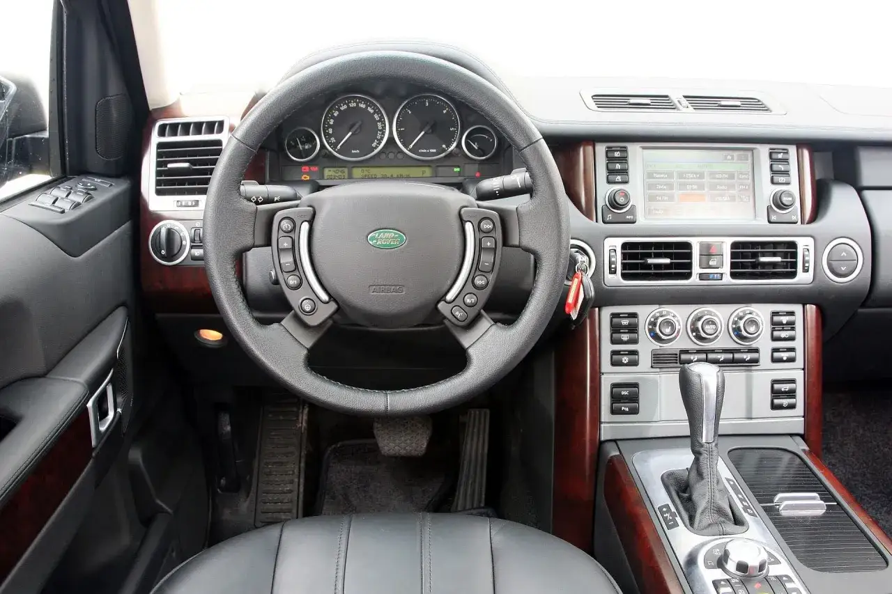 Wnętrze Range Rover L322: kierownica, deska rozdzielcza z ekranem nawigacji i panelem sterowania, dźwignia zmiany biegów.