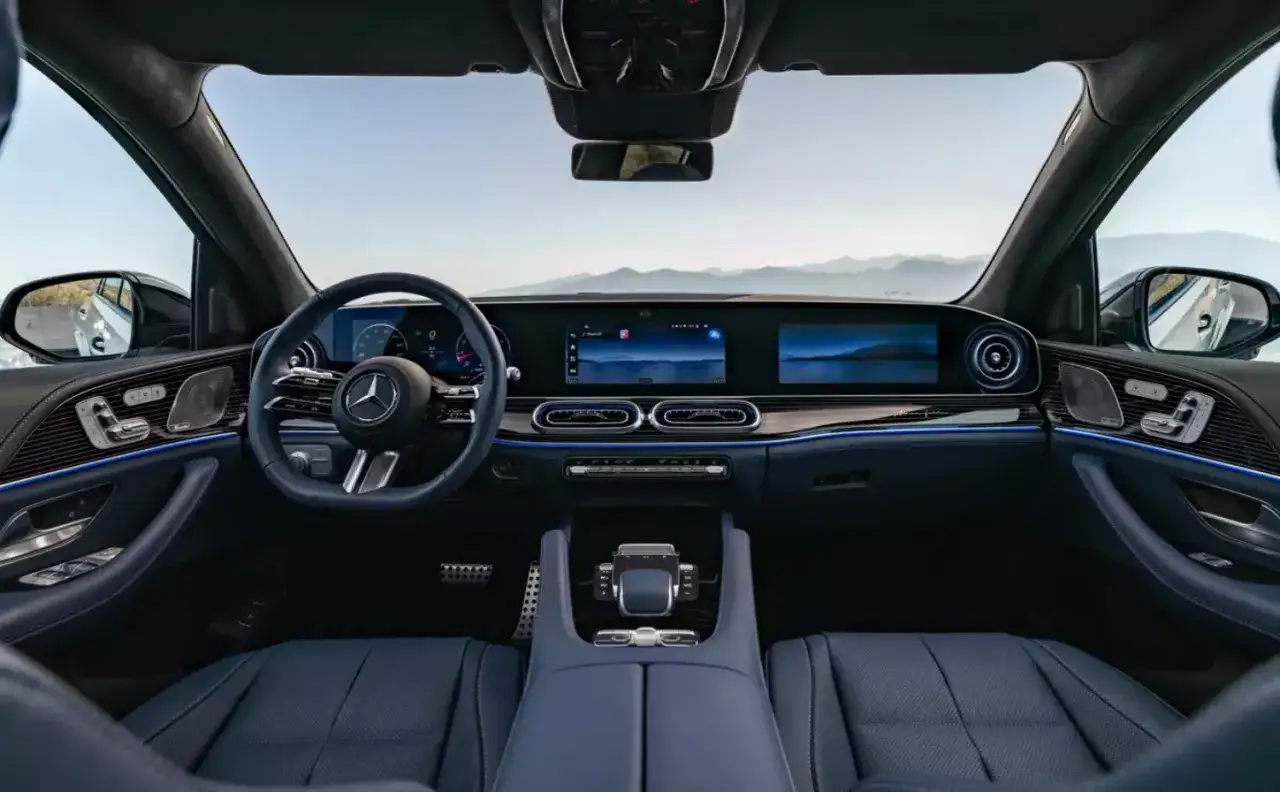 Wnętrze luksusowego Mercedes GLE 450 z niebieską skórzaną tapicerką, nowoczesnym kokpitem i dwoma dużymi ekranami.