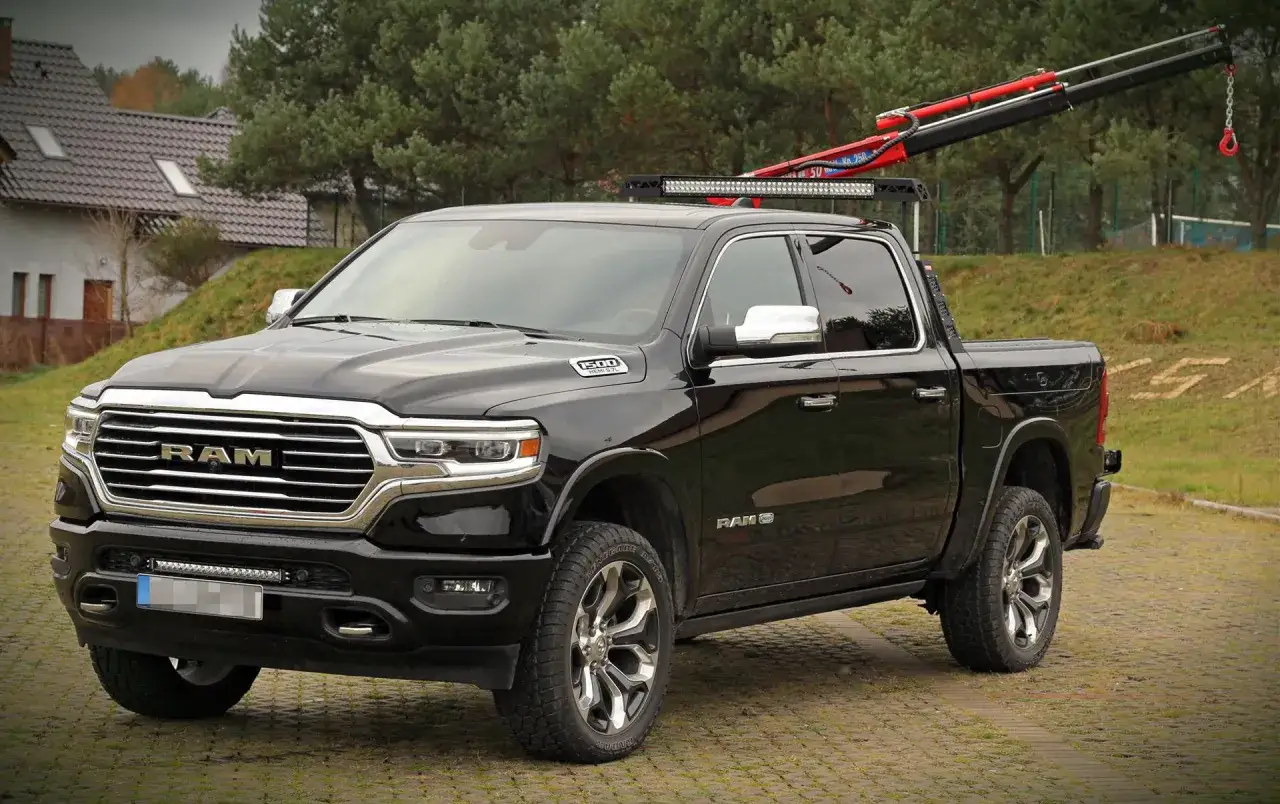 Czarny Dodge Ram 1500 z zamontowanym żurawiem i listwą LED na dachu, gotowy do pracy.