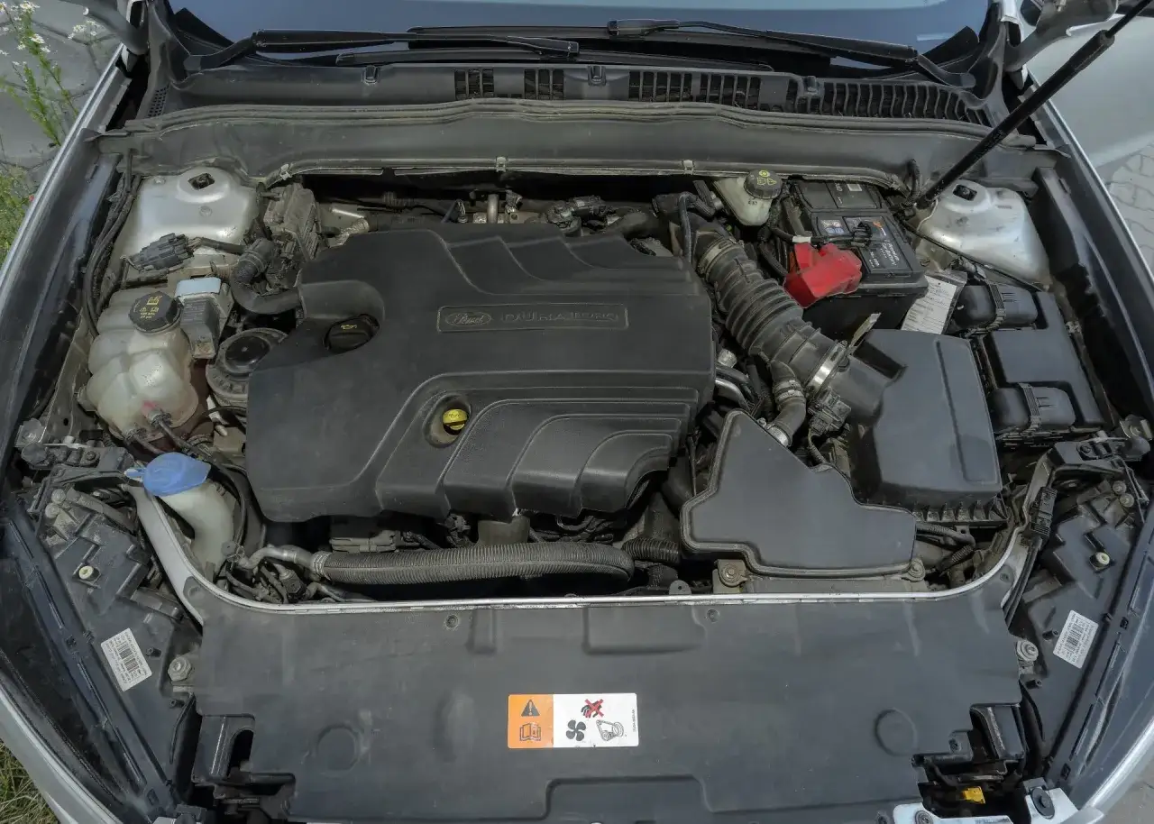 Silnik Duratorq w Fordzie Mondeo MK5 2.0 TDCI. Widoczny akumulator, zbiornik płynu chłodniczego i elementy układu dolotowego.