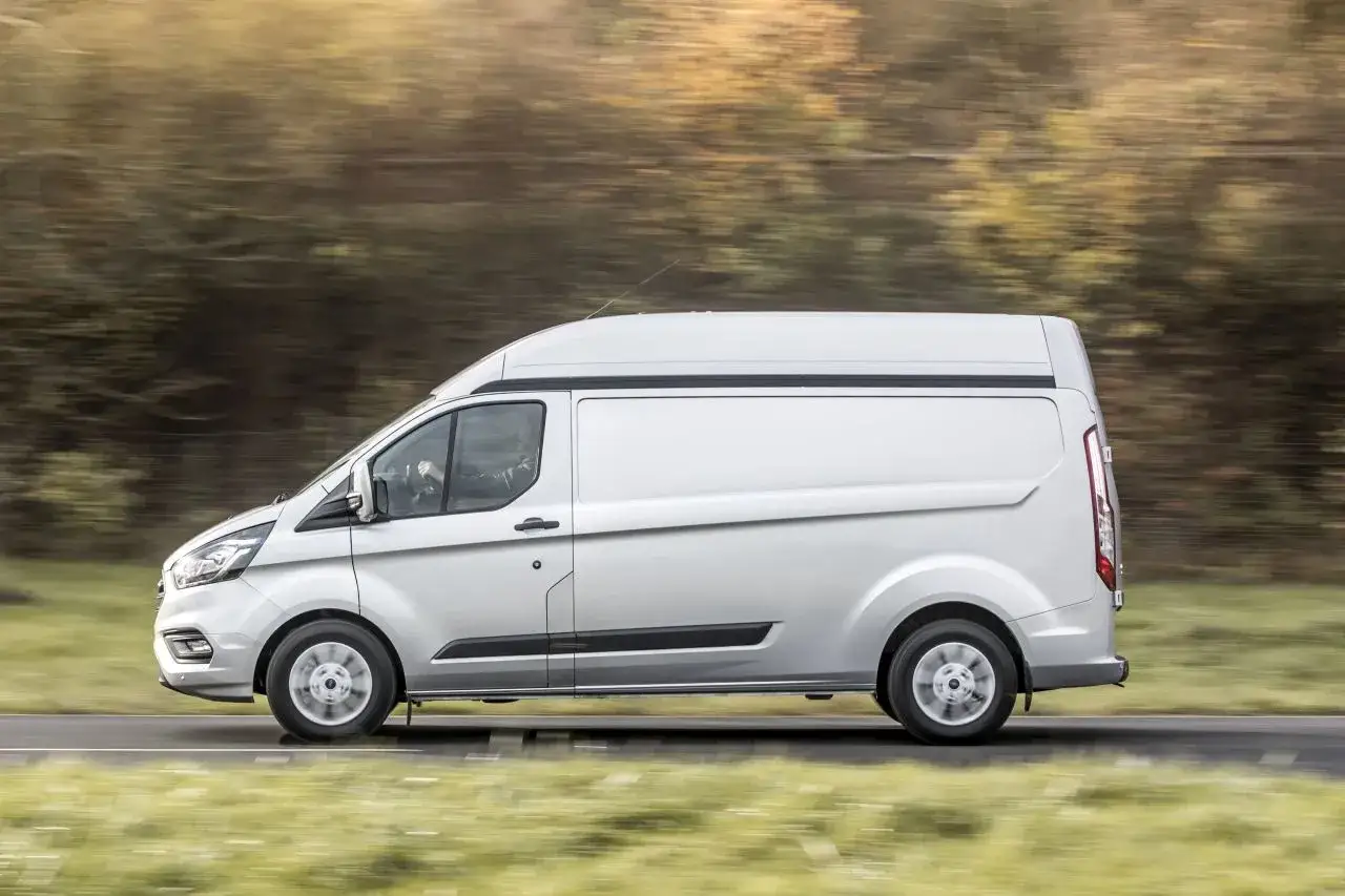 Srebrny Ford Transit Custom w ruchu, z rozmytym tłem. Idealny do pracy, jego wymiary pozwalają na przewóz wielu rzeczy.