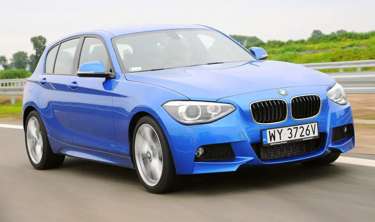 Niebieskie BMW 120 na drodze, z widocznym kierowcą w kasku.