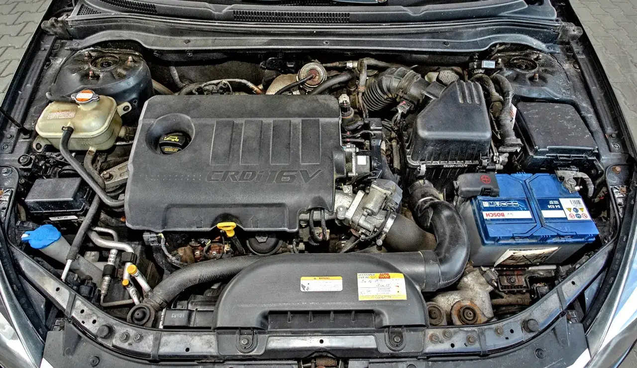 Silnik Kia Ceed 1.6 CRDi. Widoczny jest czarny plastikowy kolektor, akumulator Bosch i zbiornik płynu chłodniczego.