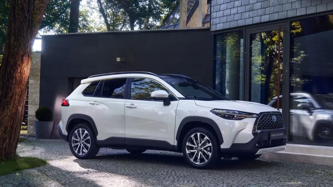 Biała Toyota Corolla Cross zaparkowana przed nowoczesnym budynkiem. Sprawdź jej wymiary!