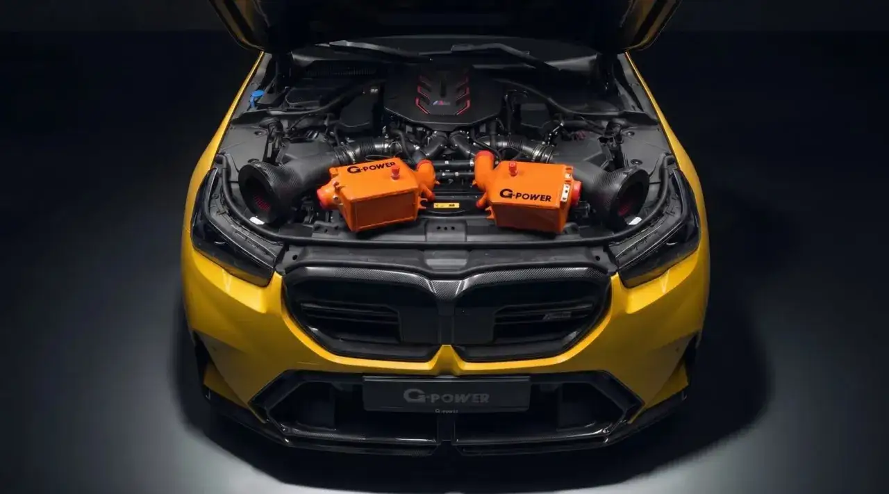 Żółte BMW M5 z otwartą maską, prezentujące pomarańczowe intercoolery G-Power i potężny silnik.
