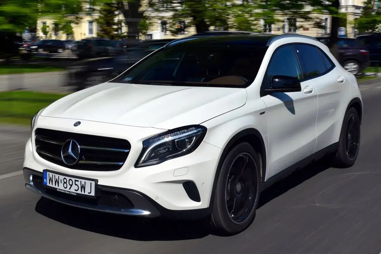 Biały Mercedes GLA w ruchu ulicznym. Wiele osób szuka informacji o mercedes gla - opinie usterki, by dowiedzieć się więcej o tym modelu.