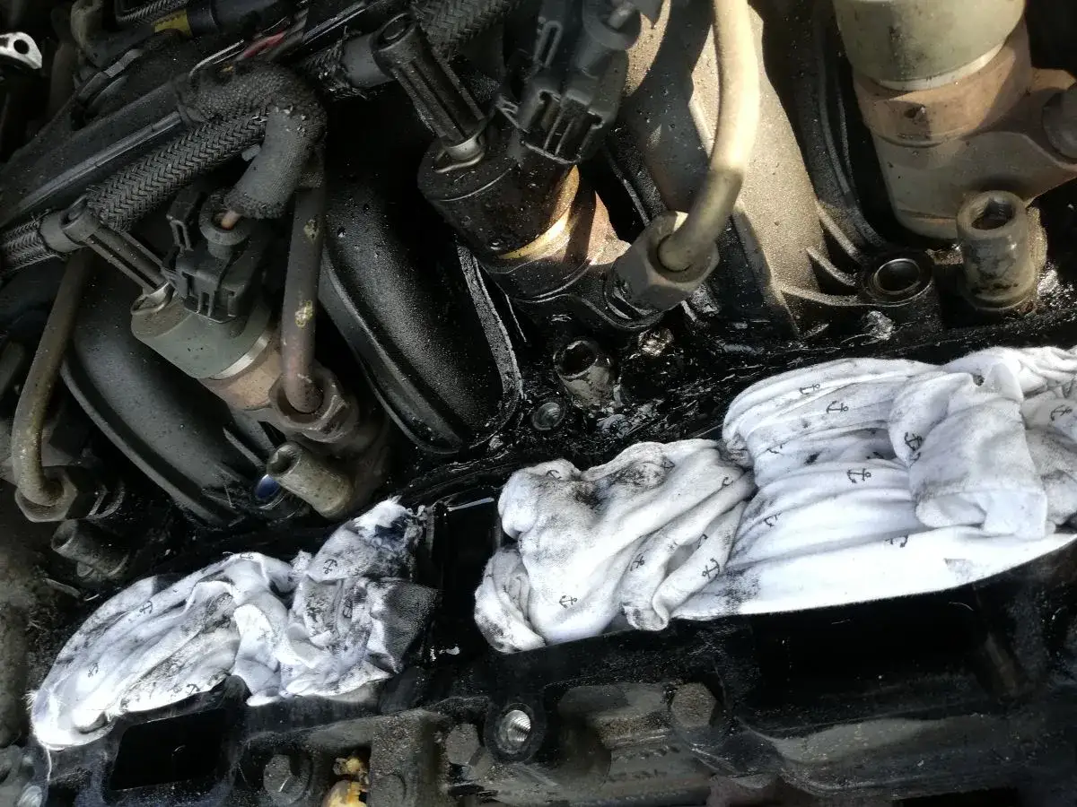 Silnik Citroen C4 1.6 HDI po awarii, widać wyciek oleju i użyte do wytarcia szmaty.
