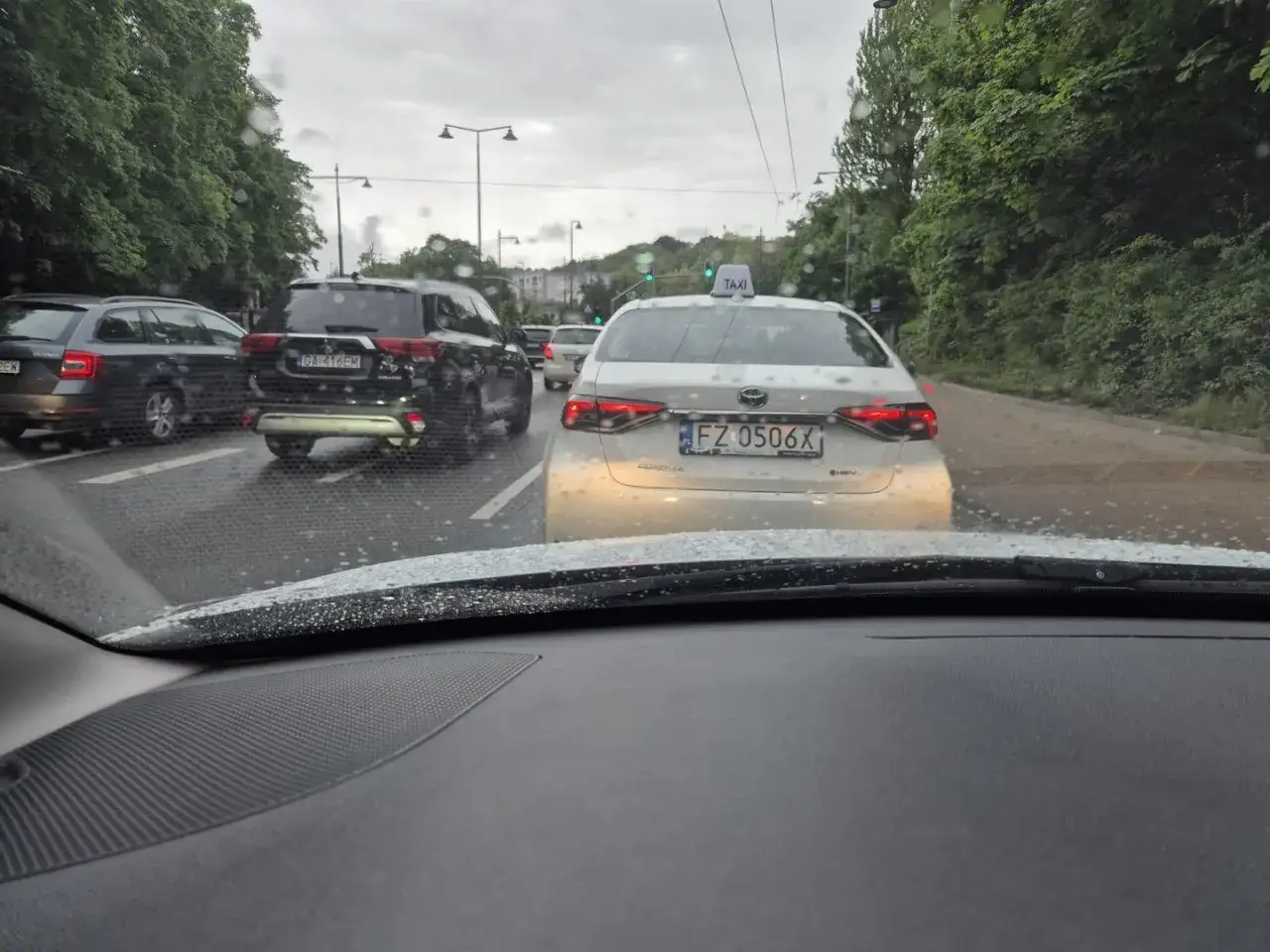 Biała taksówka z rejestracją FZ 0506X w korku.