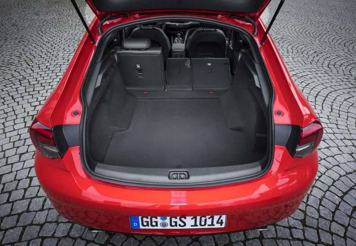 Czerwony Opel Insignia z otwartym bagażnikiem. Wnętrze pokazuje przestronność, idealną na wakacyjne wyjazdy, co potwierdzają jego wymiary.