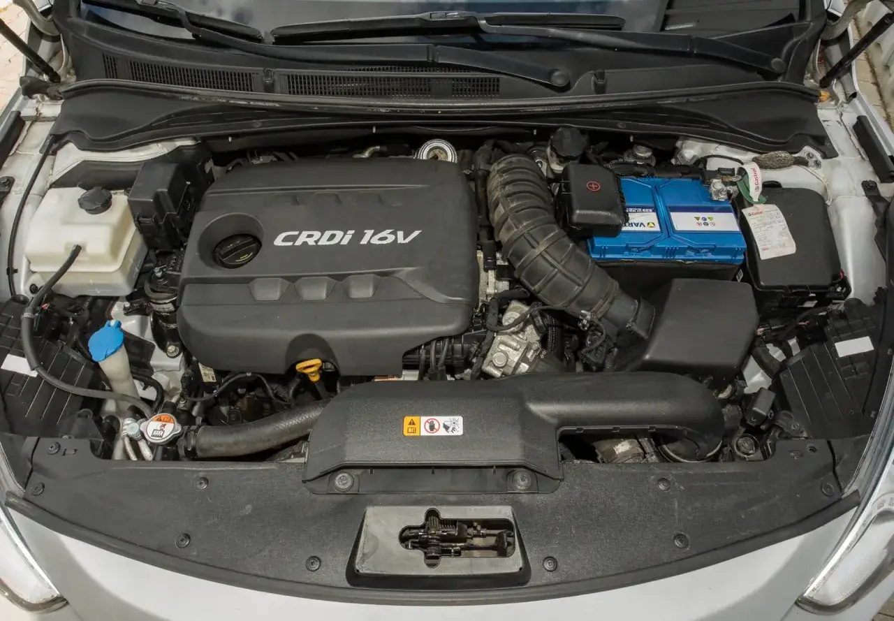 Silnik CRDi 1.7 w Kia Sportage. Widoczny akumulator, osłona silnika i elementy układu dolotowego.