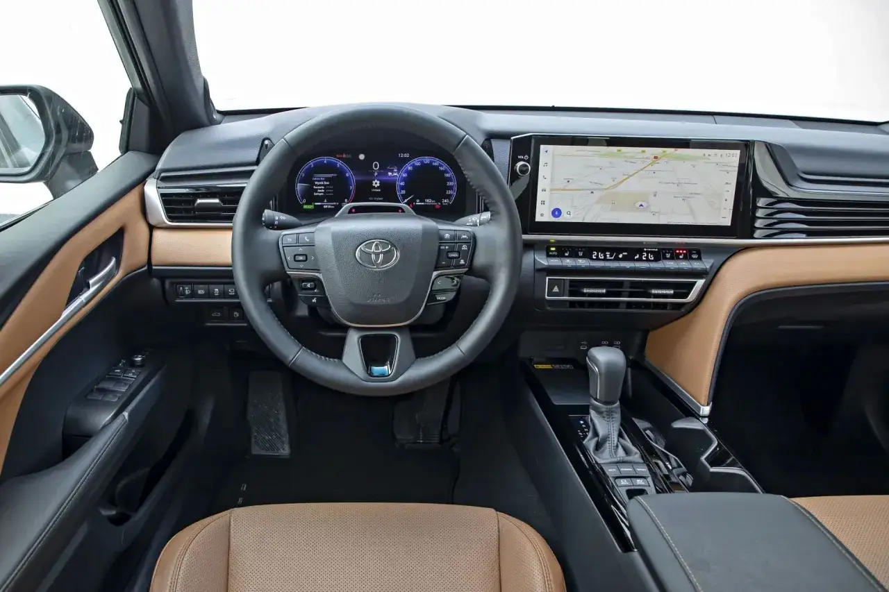 Wnętrze Toyoty Camry z brązową tapicerką i nowoczesnym ekranem nawigacji. Wiele osób szuka takich detali w toyota camry opinie.