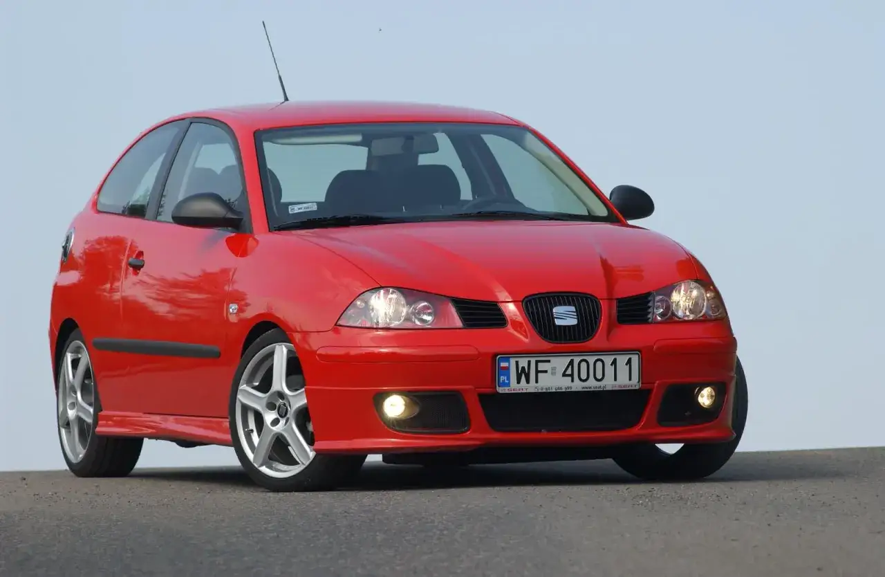 Czerwony Seat Ibiza 1.4 benzyna z felgami aluminiowymi, zaparkowany na tle błękitnego nieba.