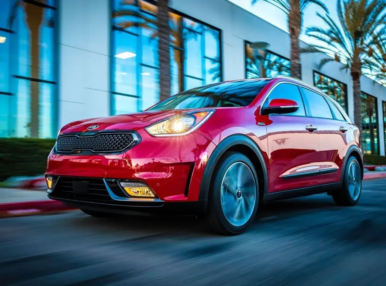 Czerwony Kia Niro w ruchu, z widocznymi światłami i felgami. Choć auto wygląda świetnie, warto pamiętać o jego potencjalnych wadach.