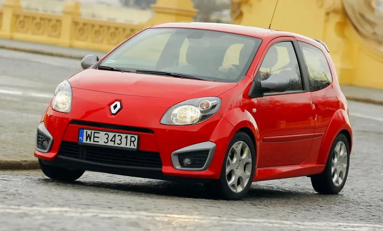 Czerwone Twingo RS na mokrej nawierzchni, z widocznym kierowcą za kierownicą.