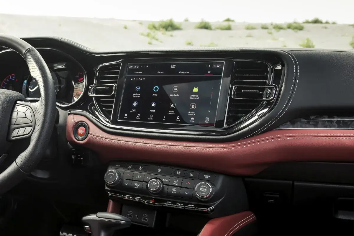 Wnętrze Dodge Durango, z ekranem multimedialnym i czerwoną skórą. Warto sprawdzić dodge durango opinie przed zakupem.