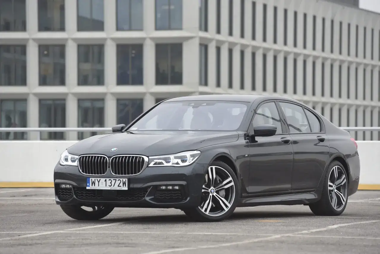 Eleganckie BMW G10 w ciemnym kolorze, zaparkowane przed nowoczesnym budynkiem.