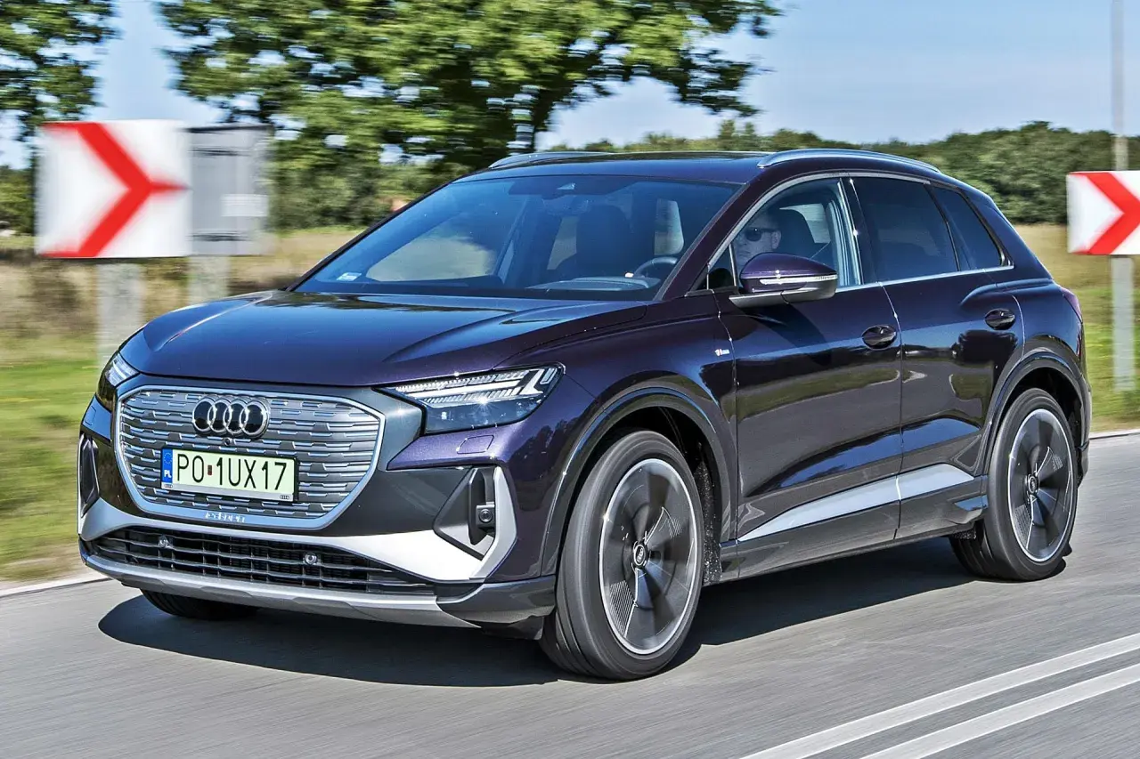 Elegancki, ciemnofioletowy audi elektryk pędzi po drodze, mijając znaki ostrzegawcze.