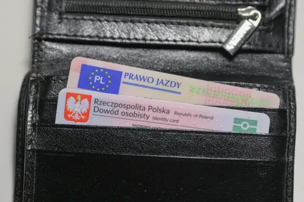 Czarny portfel z polskim dowodem osobistym i prawem jazdy. Na dokumencie prawa jazdy widnieje napis "PRAWO JAZDY" oraz symbol Unii Europejskiej.
