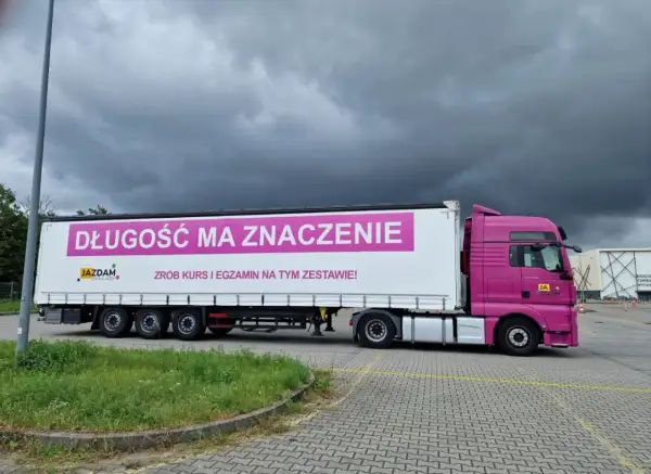 Różowa ciężarówka z napisem "Długość ma znaczenie. Zrób kurs i egzamin na tym zestawie!" zachęca do zdobycia prawa jazdy kat C+E. Całkowity koszt kursu i egzaminu jest tu kluczowy.