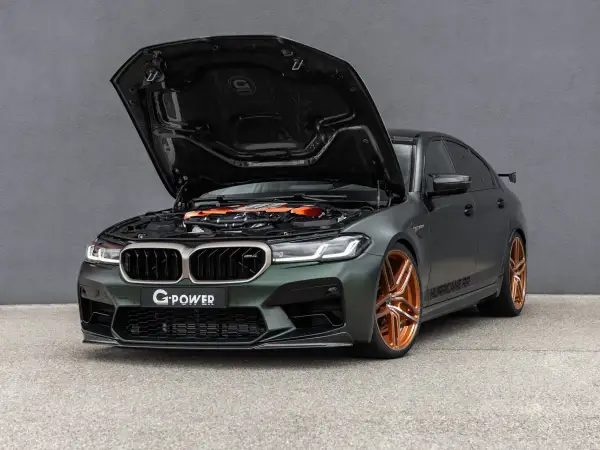Mocarny BMW M5 G Power z otwartą maską, prezentujący pomarańczowy silnik i miedziane felgi.