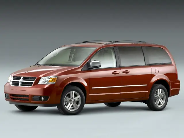 Pomarańczowy Dodge Grand Caravan z chromowanymi listwami i relingami dachowymi, gotowy na rodzinną podróż.